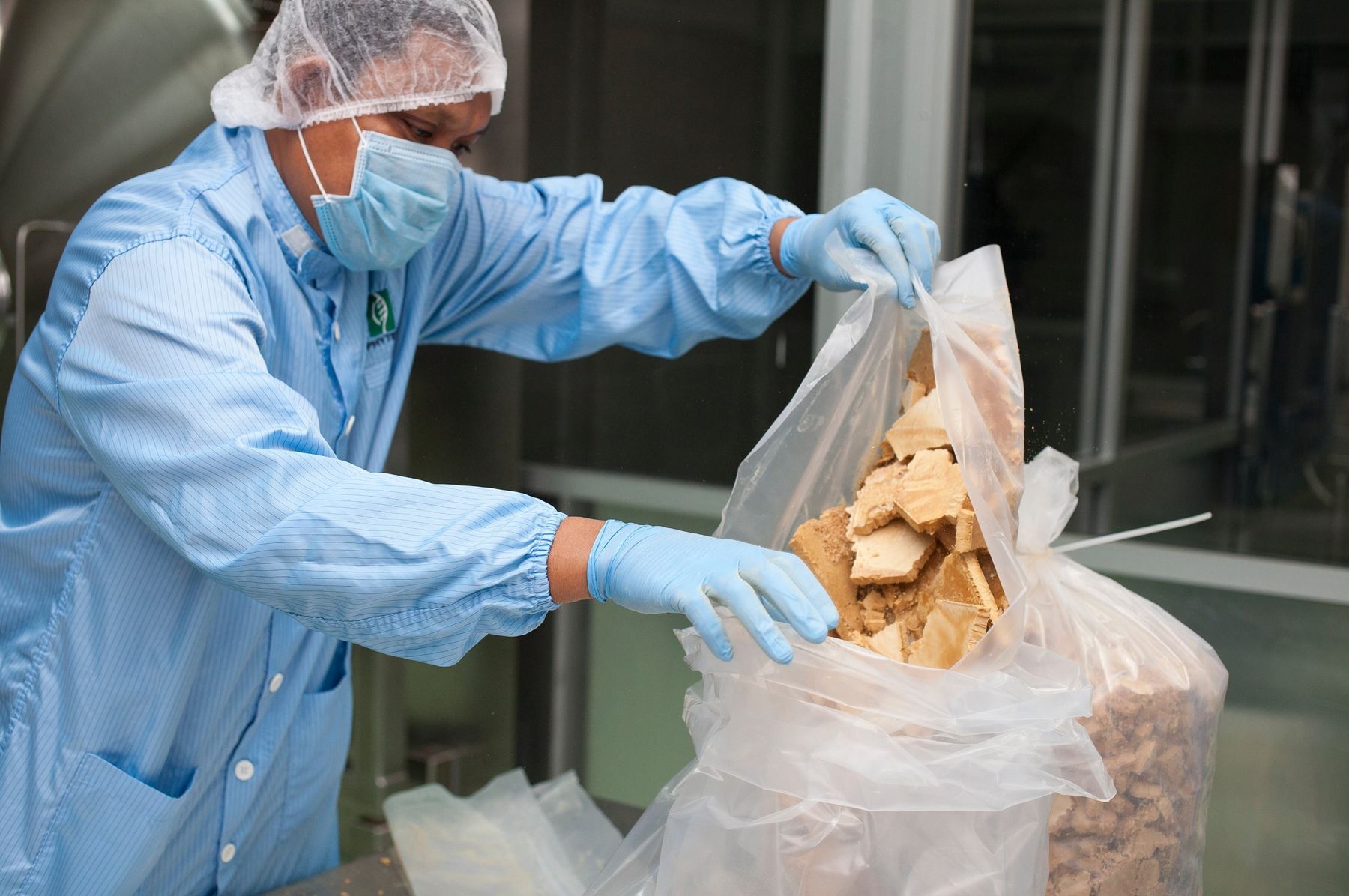 A production worker handling dried extract at the Biotropics plant